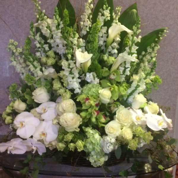 Large white and green floral arrangement with orchids and calla lilies