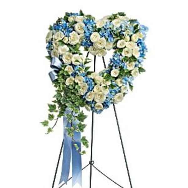Heart-shaped floral wreath on a standing easel with blue and white flowers