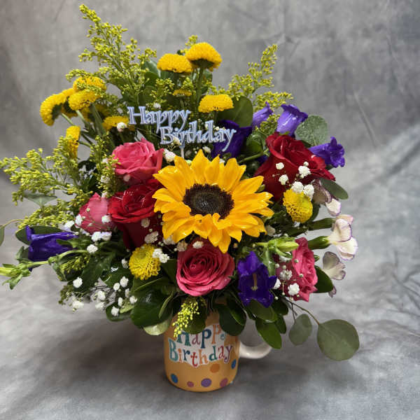 Colorful birthday bouquet in a mug with roses and a sunflower