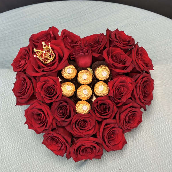 Heart-shaped red rose arrangement with gold-wrapped chocolates in the center