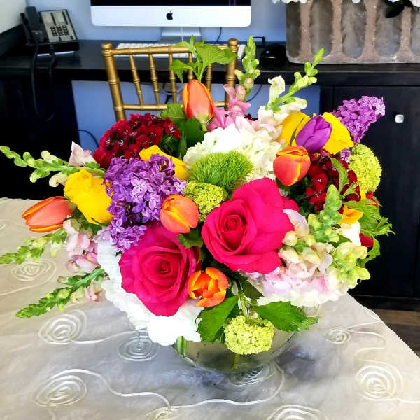 Bright mixed bouquet of roses, tulips, and hydrangea in a glass vase