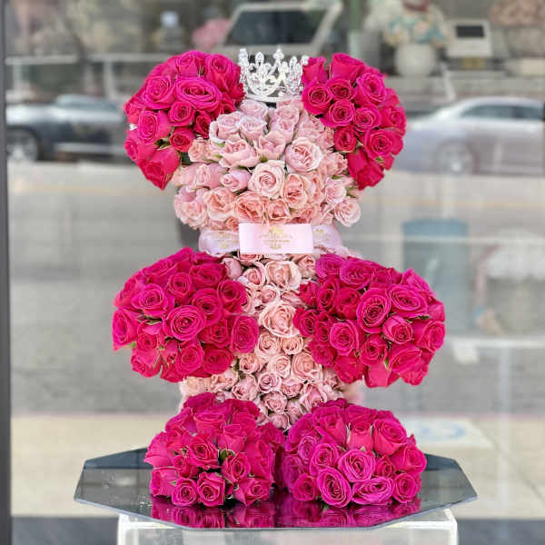 Tiered arrangement of pink and hot pink roses with a crown topper