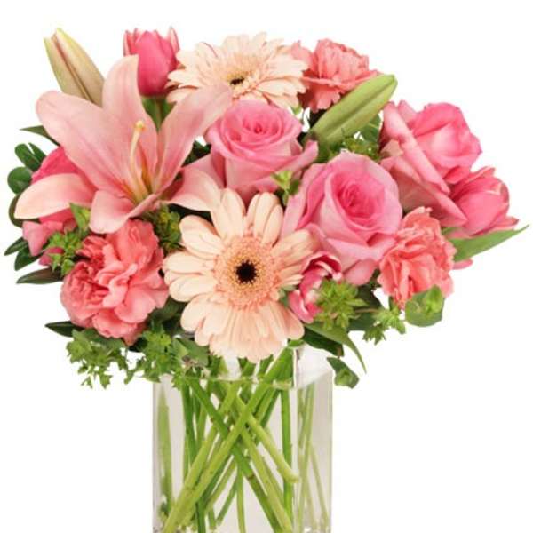Pink and peach lilies, roses, gerberas, and carnations in a clear glass vase