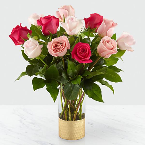 Pink and red roses in a clear glass vase with a gold wrap