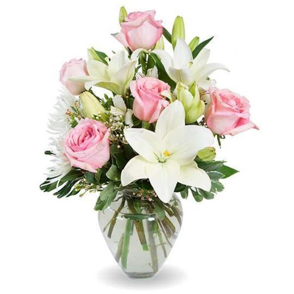 Pink roses and white lilies arranged in a clear glass vase