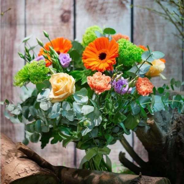 Bouquet of orange gerbera daisies and pastel roses with greenery