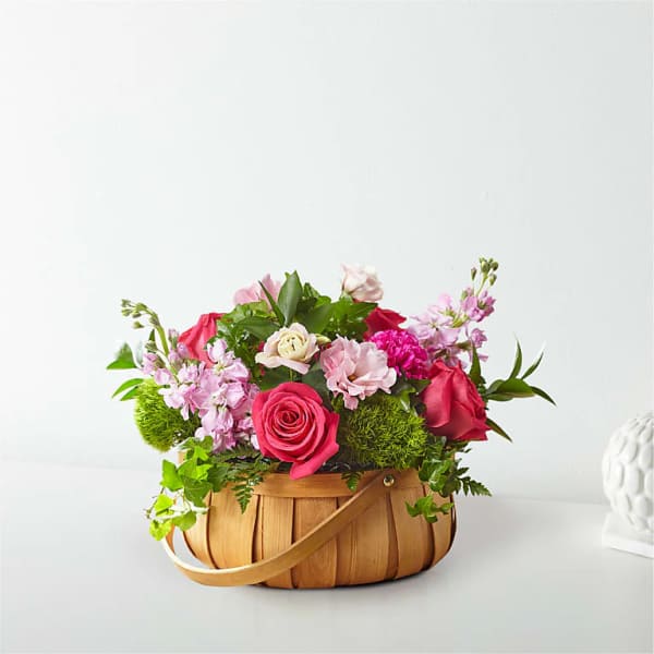 Pink and red flower arrangement in a woven basket