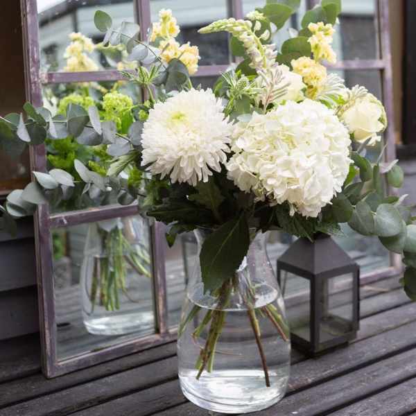 White flowers in a clear glass vase with eucalyptus