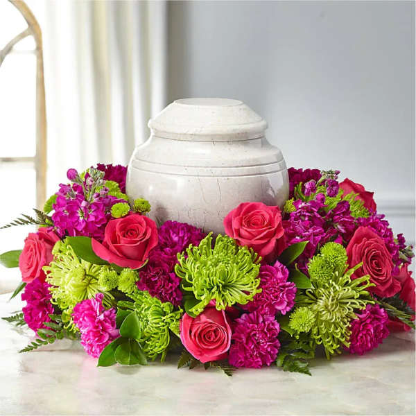 Pink roses and magenta flowers arranged around a white urn