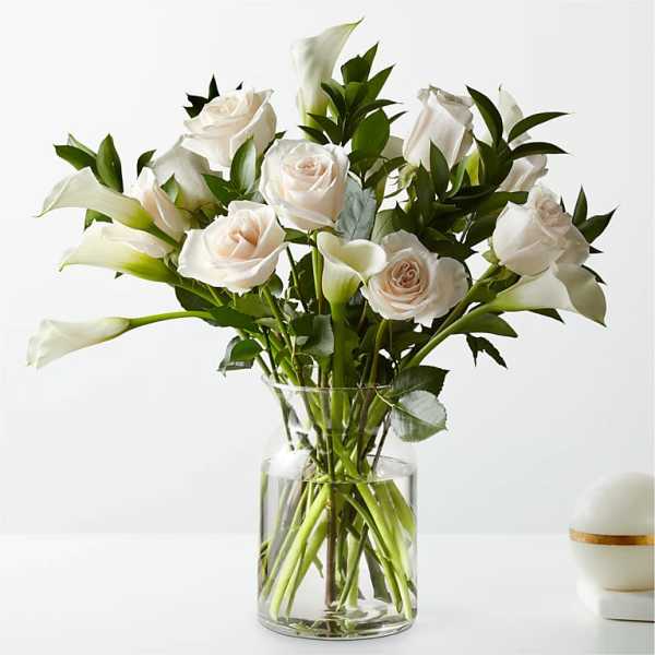 White roses and calla lilies in a clear glass vase