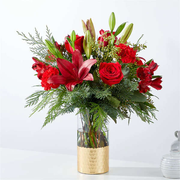 Red roses and lilies in a clear glass vase with gold wrap