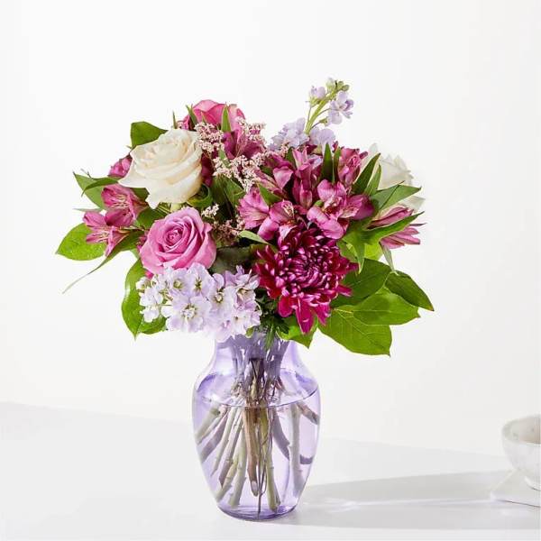 Pink and white mixed bouquet in a purple glass vase