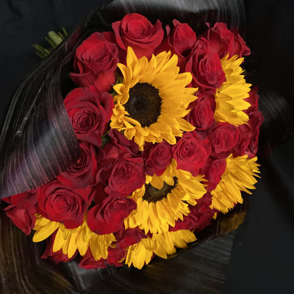 Bouquet of red roses and yellow sunflowers wrapped in black paper