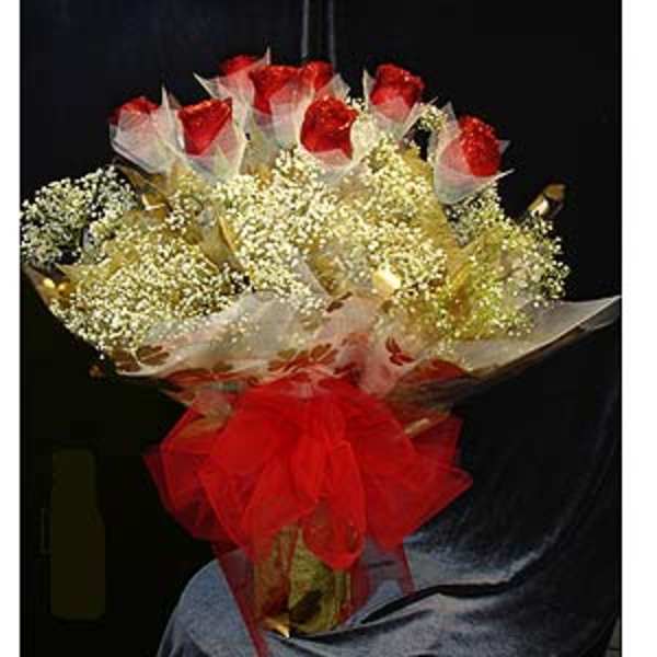 Bouquet of red roses wrapped in white mesh with a red bow