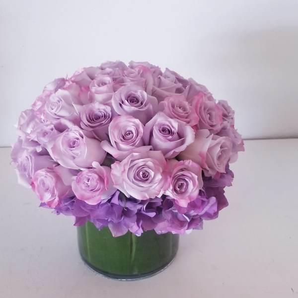 Round bouquet of pink and lavender roses in a green vase