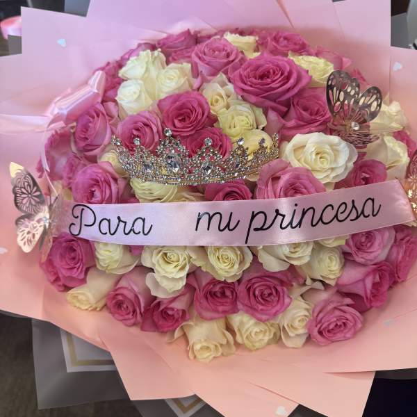 Pink and white rose bouquet with a tiara and ribbon reading "Para mi princesa"