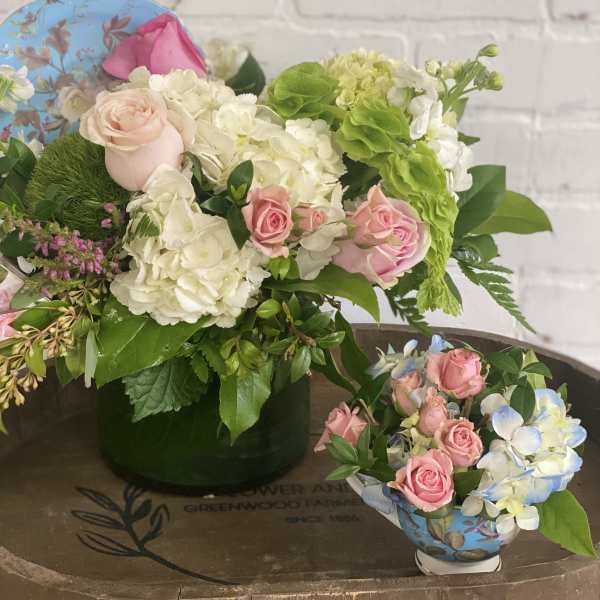 Pink roses and white hydrangeas arranged in a vase with greenery