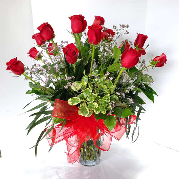 Red roses arranged in a clear glass vase with a red ribbon