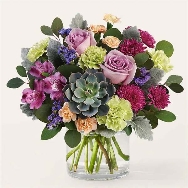 Mixed bouquet with roses, carnations, and a succulent in a glass vase