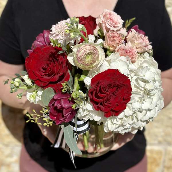Bouquet of red and blush flowers in a clear glass vase