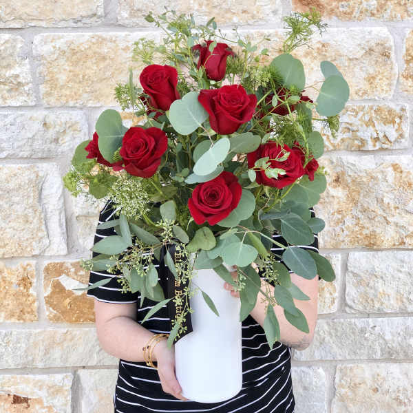 Bouquet of red roses and eucalyptus in a white vase