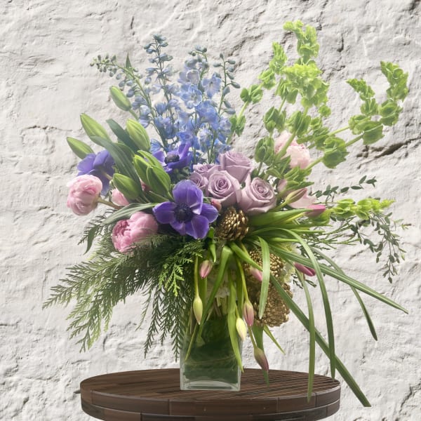 Bouquet of purple, pink, and blue flowers in a clear glass vase