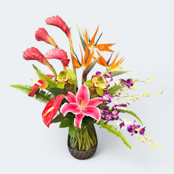 Tropical bouquet with pink lilies, orange birds of paradise, and purple orchids in a glass vase