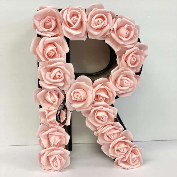 Pink rose-covered letter R decoration on a black base