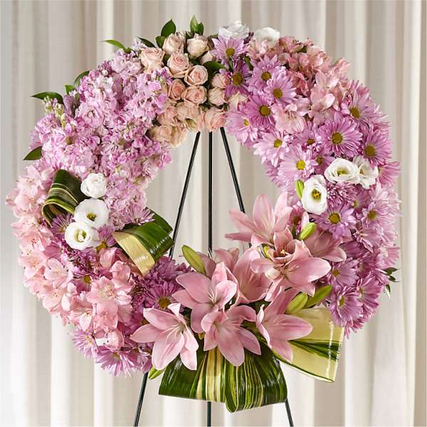 Pink floral wreath on a black easel with lilies and daisies