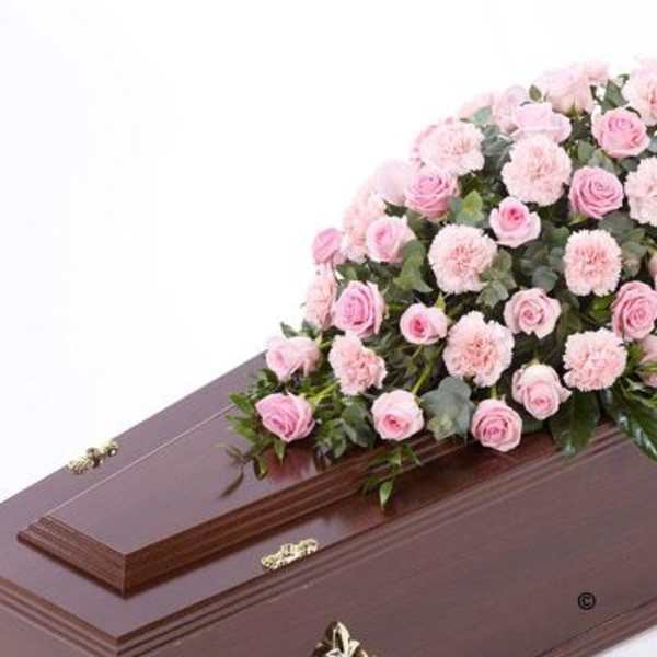 Pink roses and carnations arranged on a brown casket