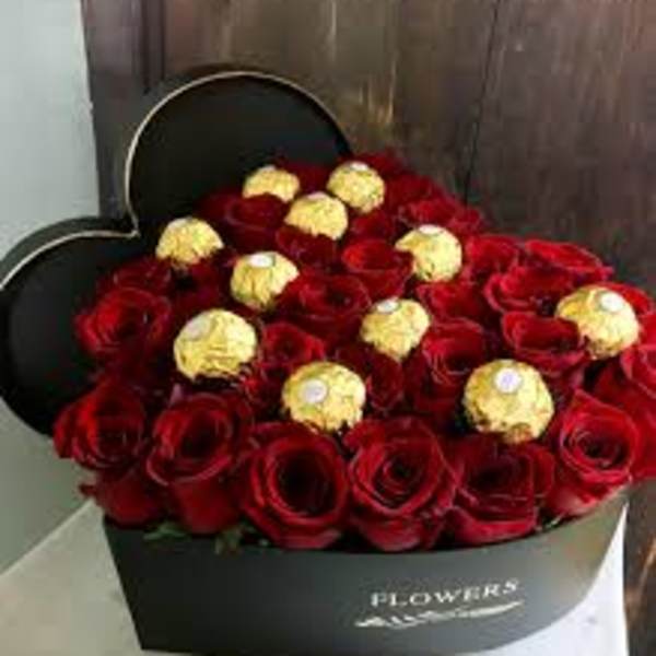 Heart-shaped box filled with red roses and gold-wrapped chocolates
