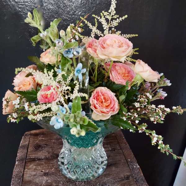 Pink roses in a glass vase with blue accent flowers