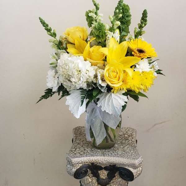 Yellow and white flower arrangement in a clear glass vase