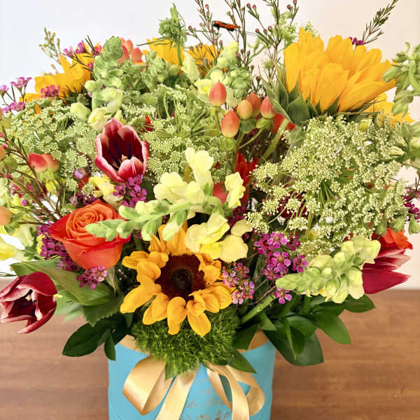 Colorful mixed bouquet in a blue hatbox with a gold ribbon