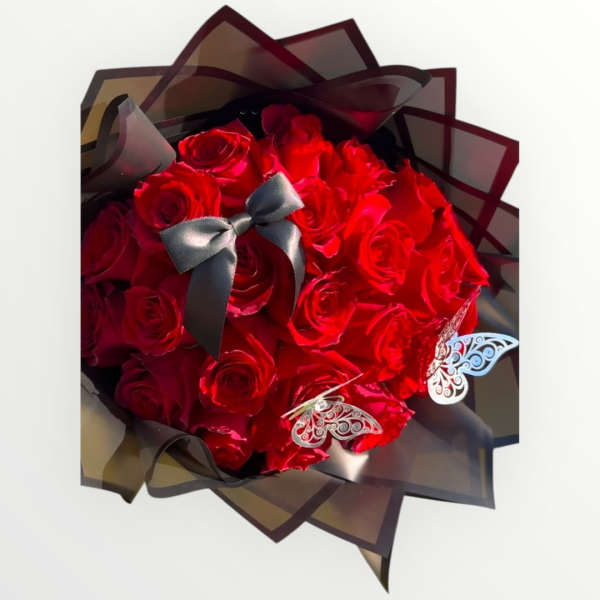 Bouquet of red roses wrapped in dark translucent paper with a black ribbon