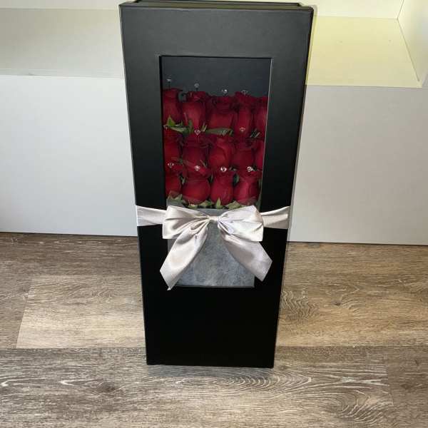 Black gift box with red roses and a silver ribbon bow