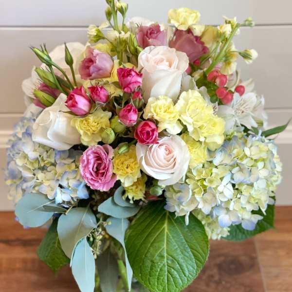 Mixed pastel bouquet with roses, hydrangeas, and carnations in a glass vase