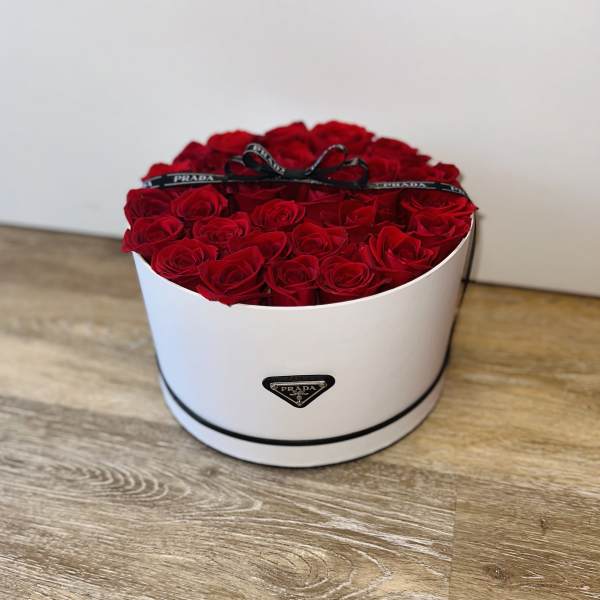 Round box filled with red roses and a black ribbon