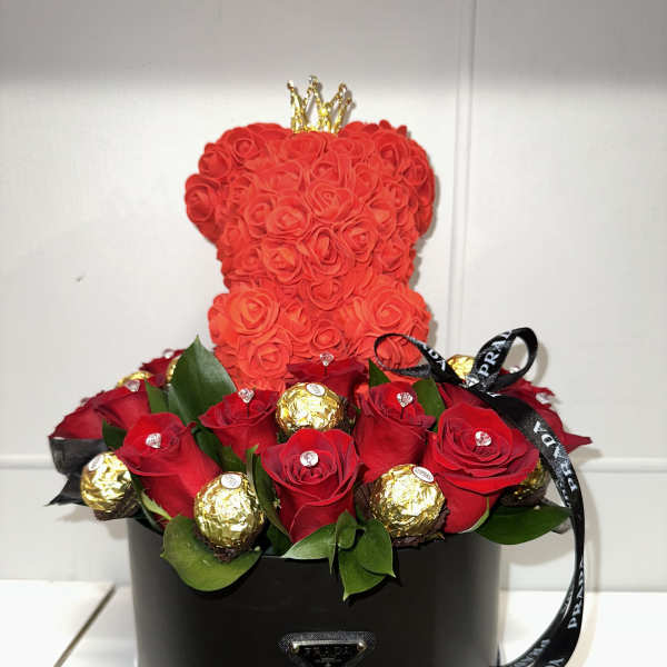 Red rose arrangement in a black round box with a small crown topper
