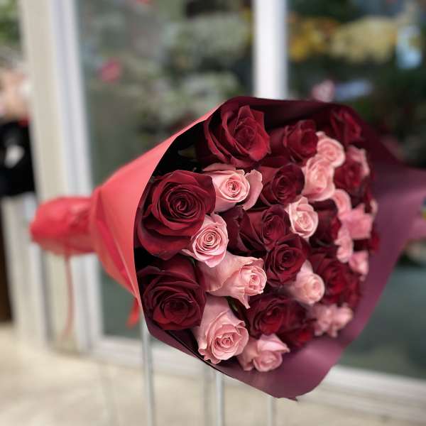 Bouquet of red and pink roses wrapped in burgundy paper