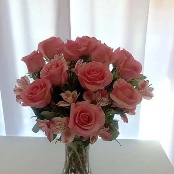 Pink roses and small striped flowers in a clear glass vase