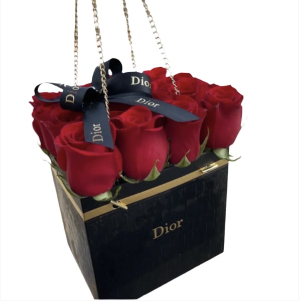 Red roses arranged in a black Dior gift bag with ribbon handles