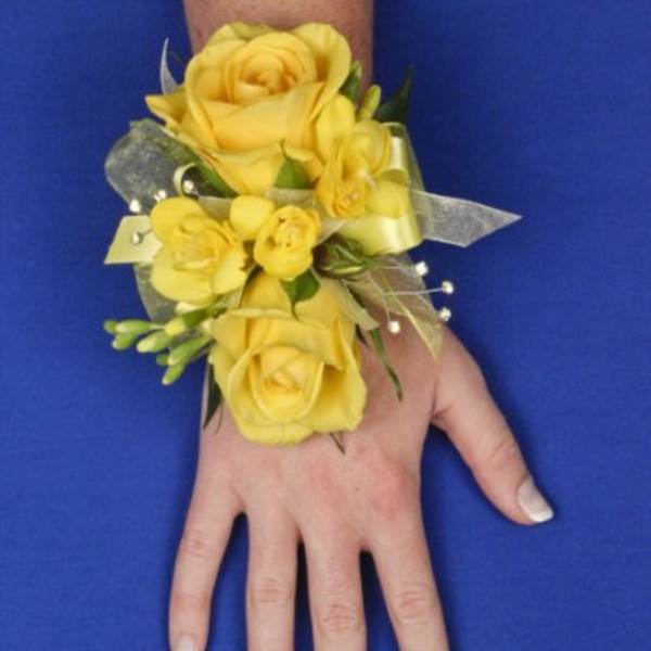 Yellow rose wrist corsage with ribbon on a person’s hand