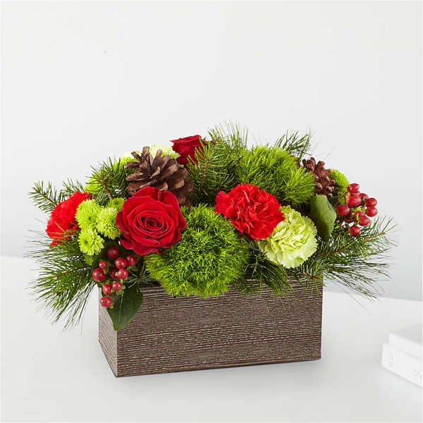 Low floral arrangement with red roses, carnations, pinecones, and greenery in a rectangular box