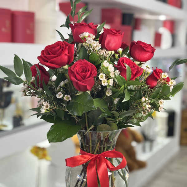 Red roses in a clear glass vase with a red ribbon