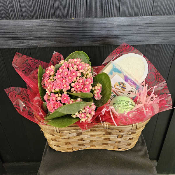 Pink flowering plant in a wicker basket with bath gift items
