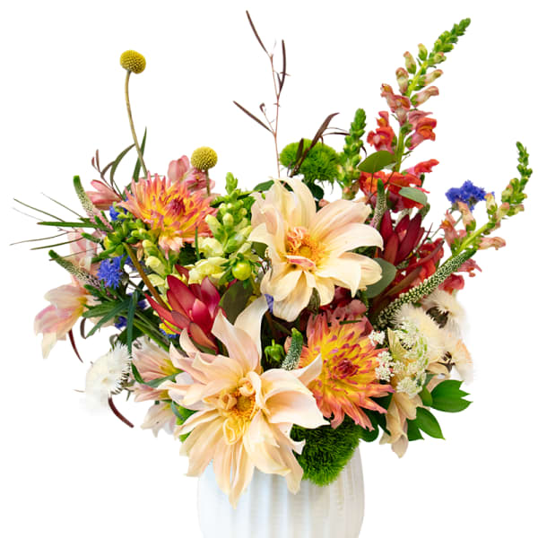 Mixed bouquet of peach, pink, yellow, and blue flowers in a white vase