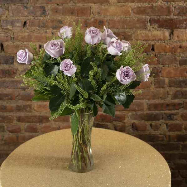 Lavender roses arranged in a clear glass vase