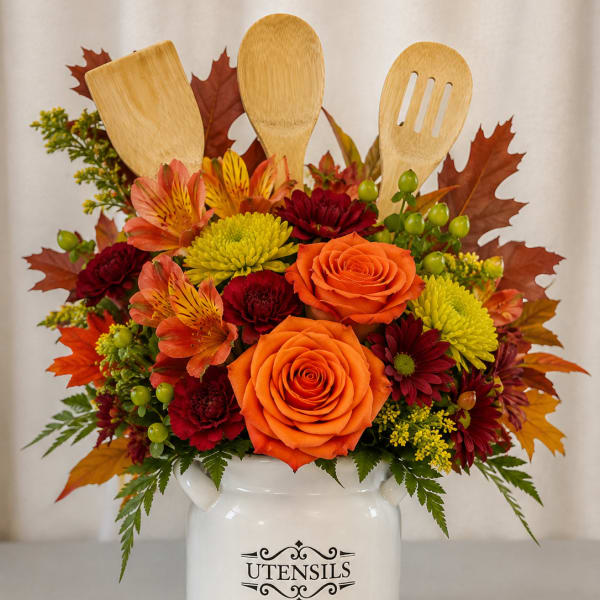Autumn floral arrangement in a white utensil holder with wooden kitchen tools