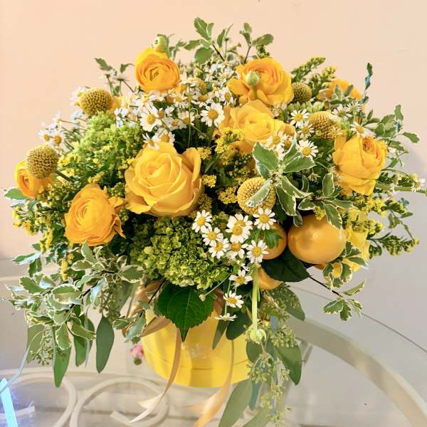 Yellow roses and small white daisies arranged in a yellow vase